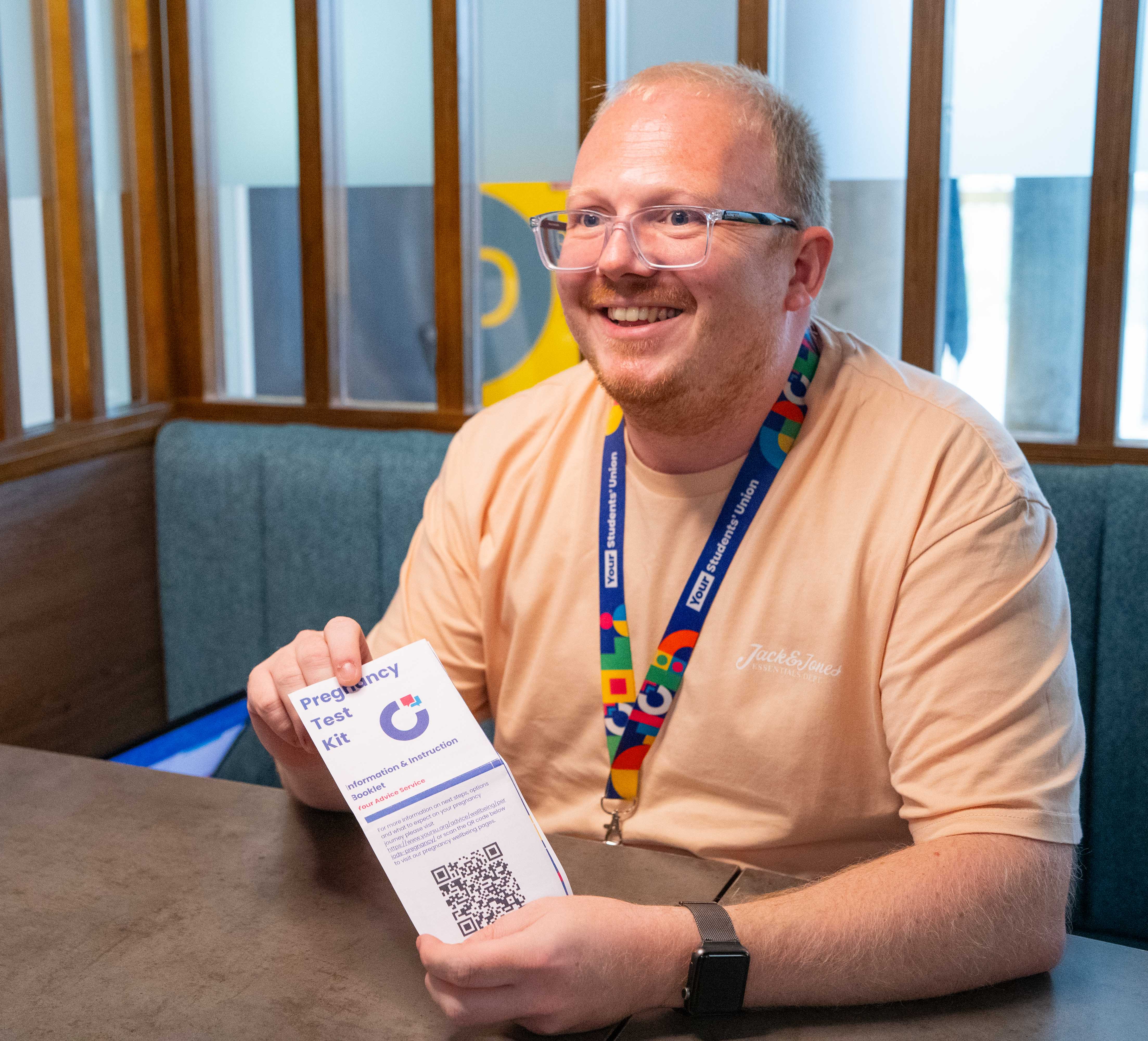Your Advice Service staff member holding a pregnancy test kit leaflet.