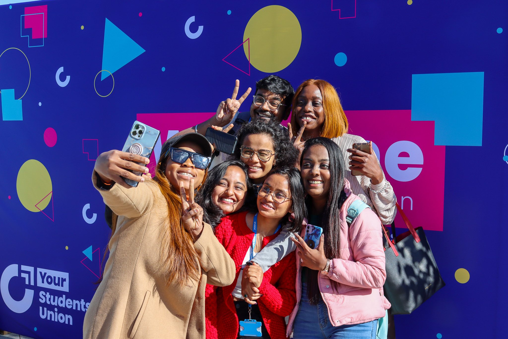 Group of students taking selfie with the Your SU banner in the background.