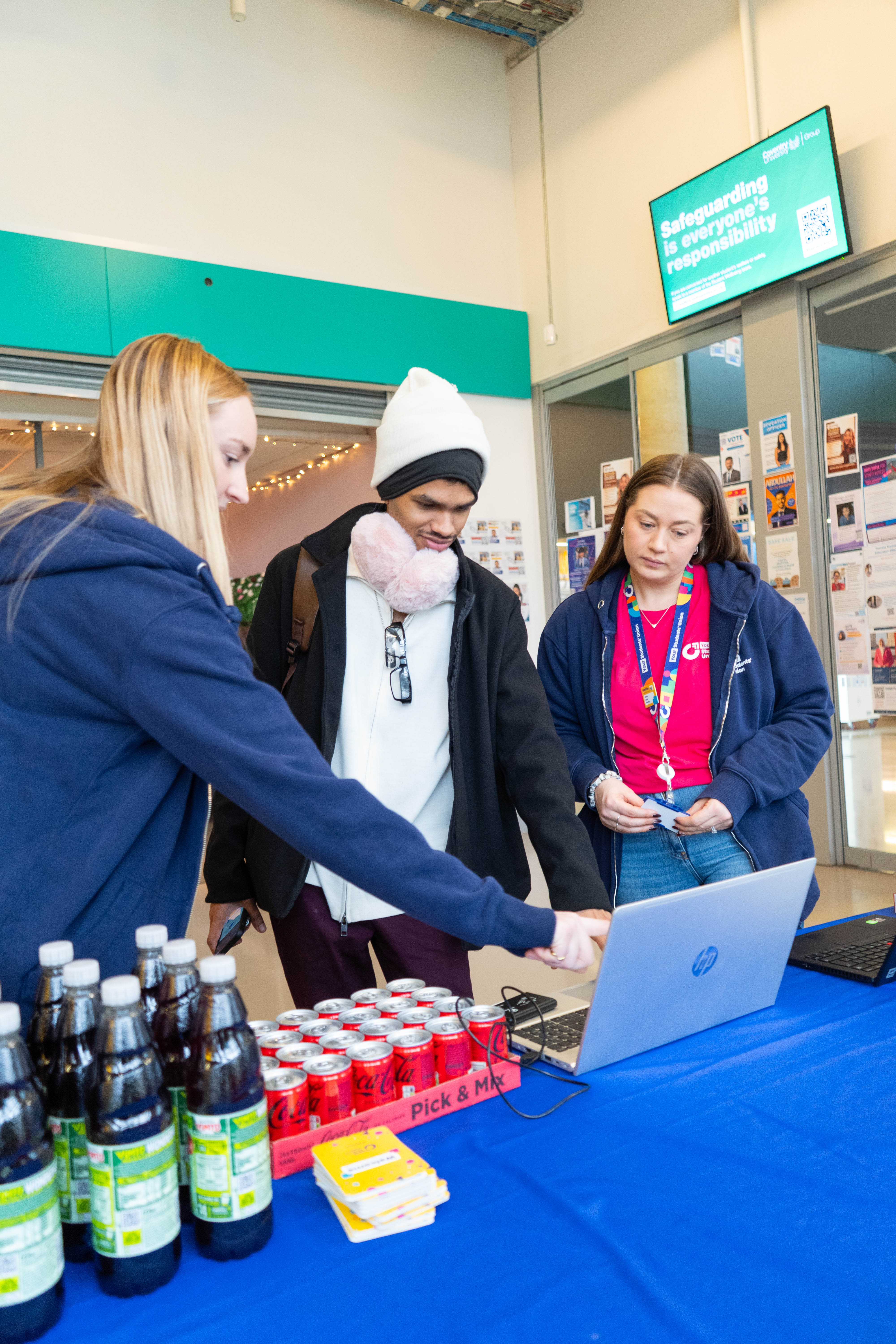 A person pointing at a laptop screen with two others watching.