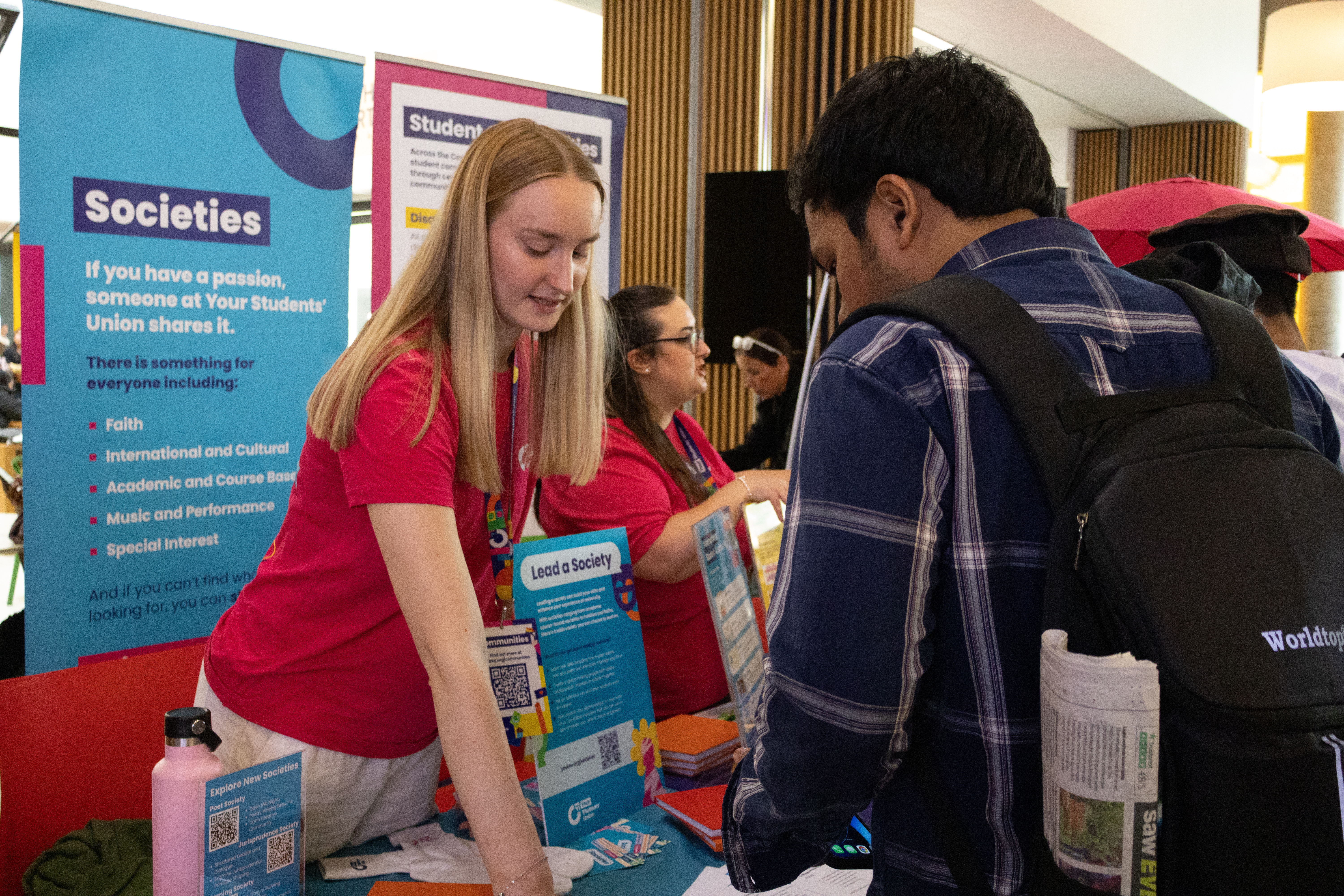 A person getting information on societies by a member of Your Students' Union staff.