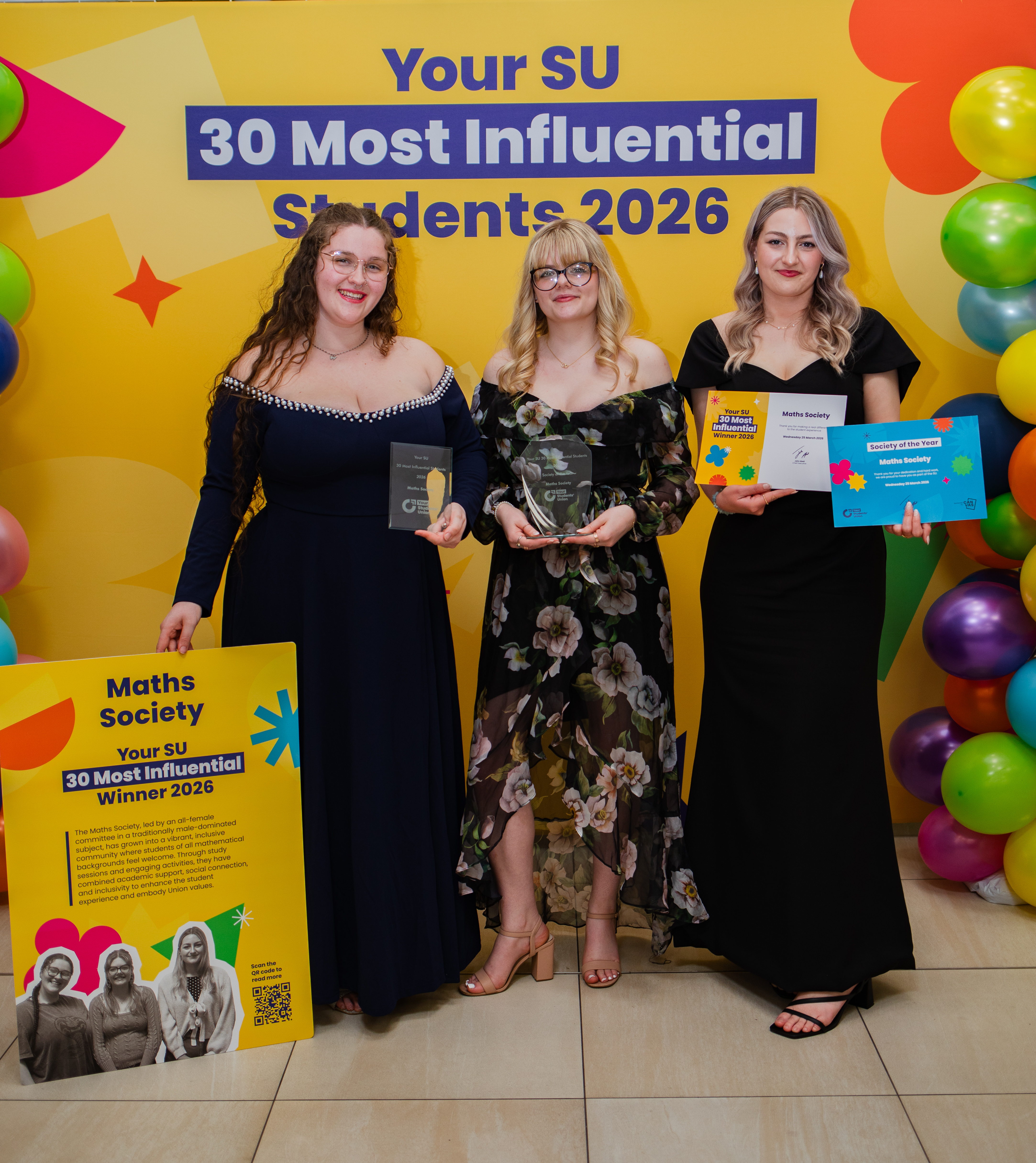 Three people standing and holding up awards.