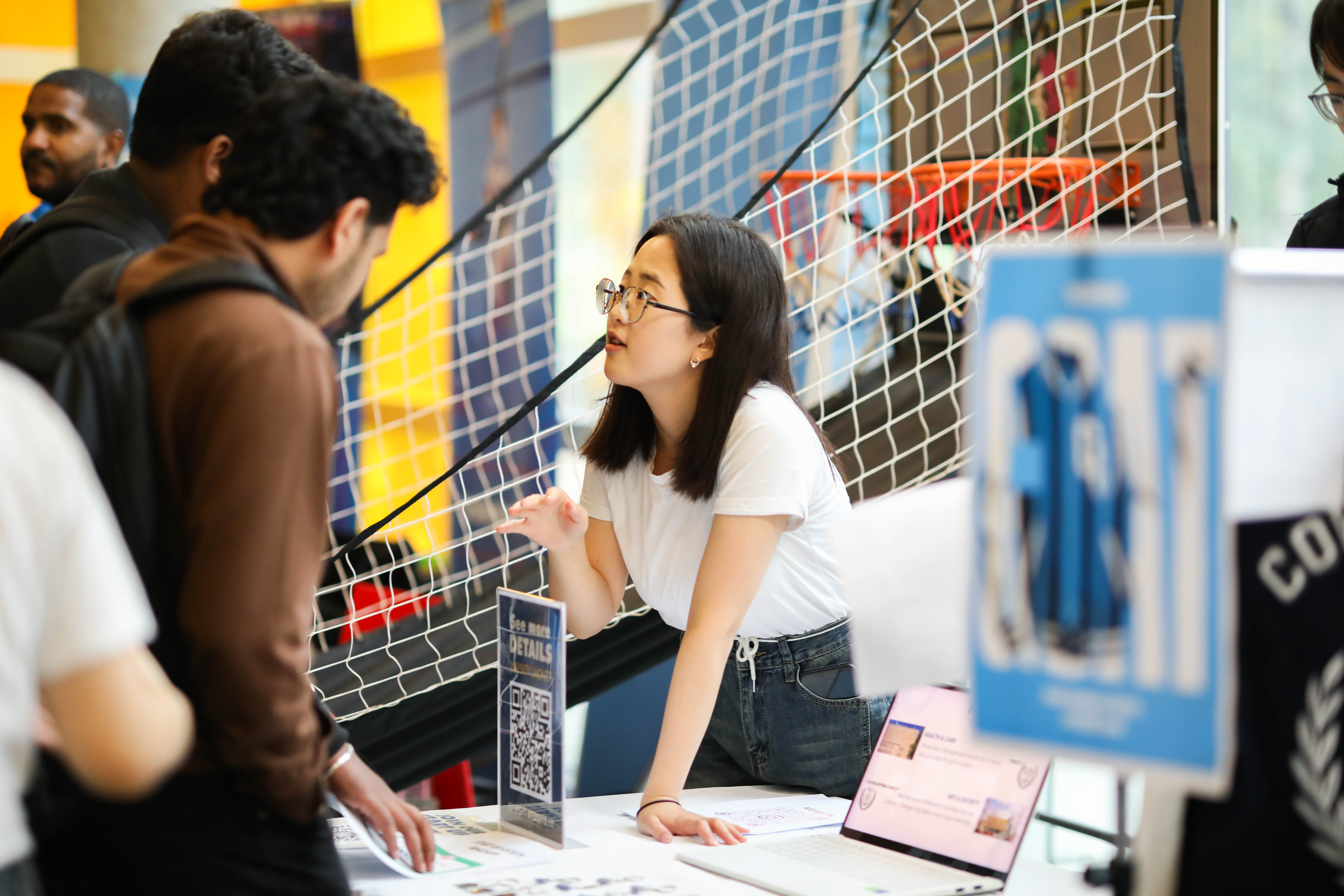 A person leaning over a table speaking to other people.
