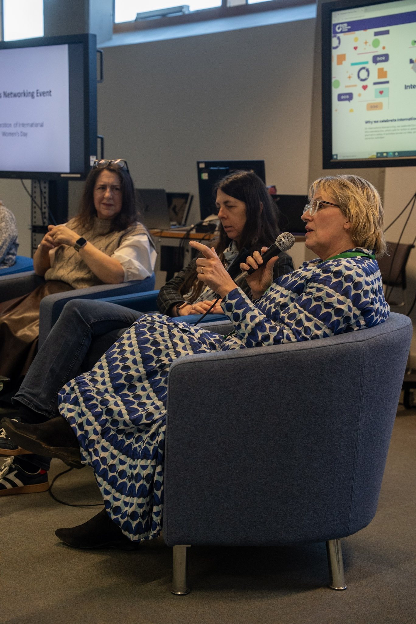 Three people sitting down, with one talking into a microphone.