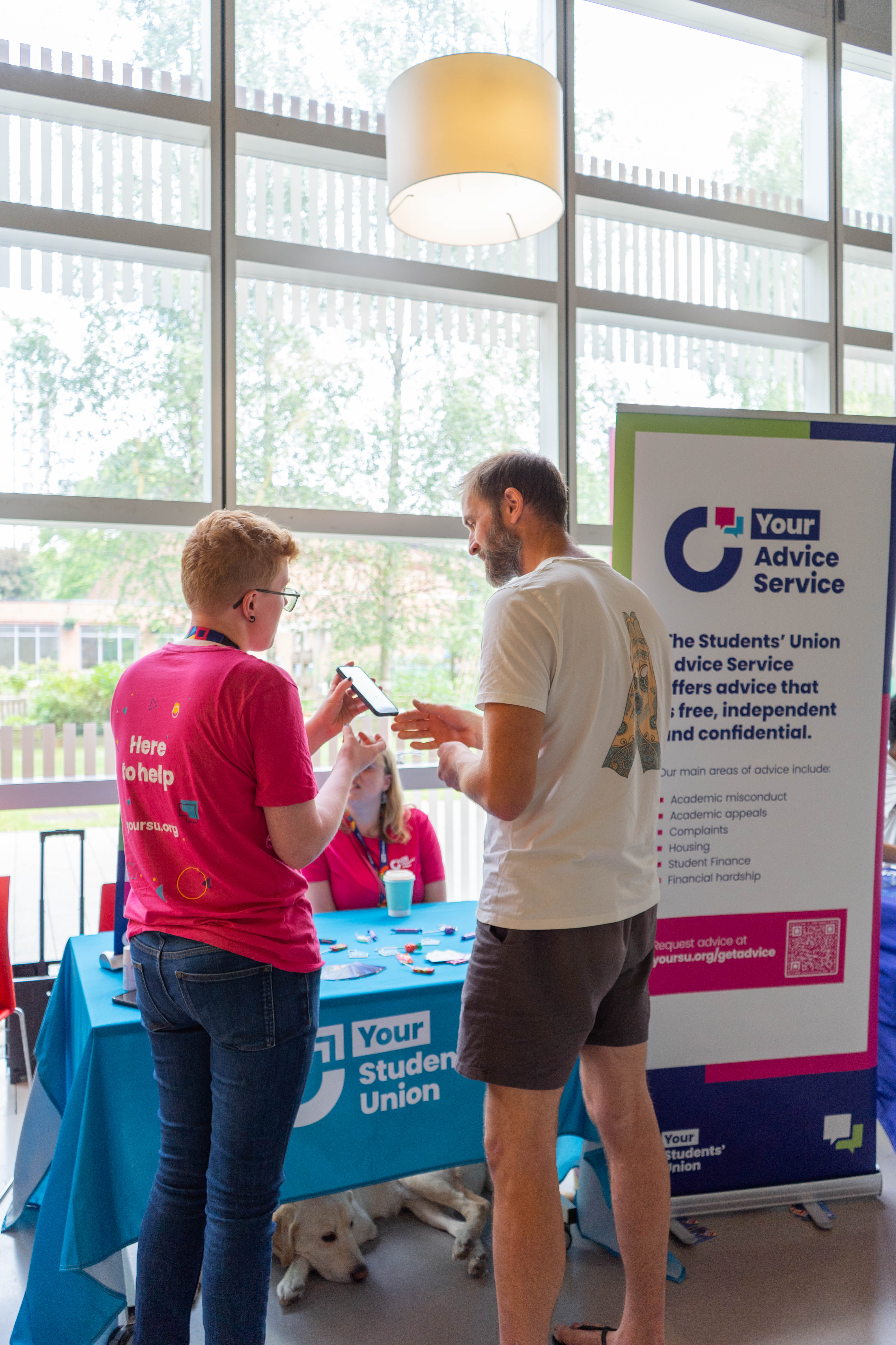 Two people talking and looking at a mobile phone.