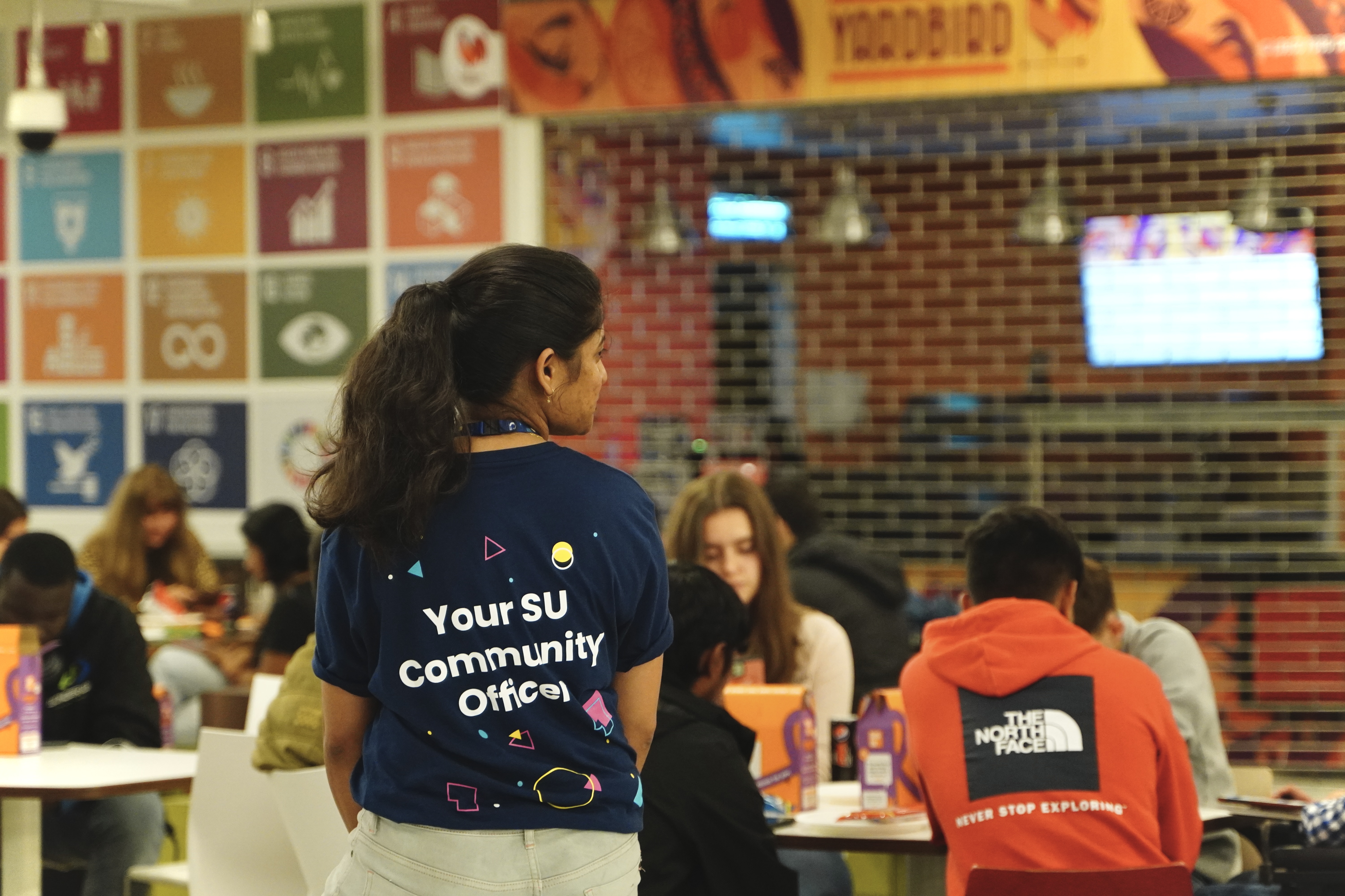 Person facing away from the camera with a shirt reading: "Your SU Community Officer".