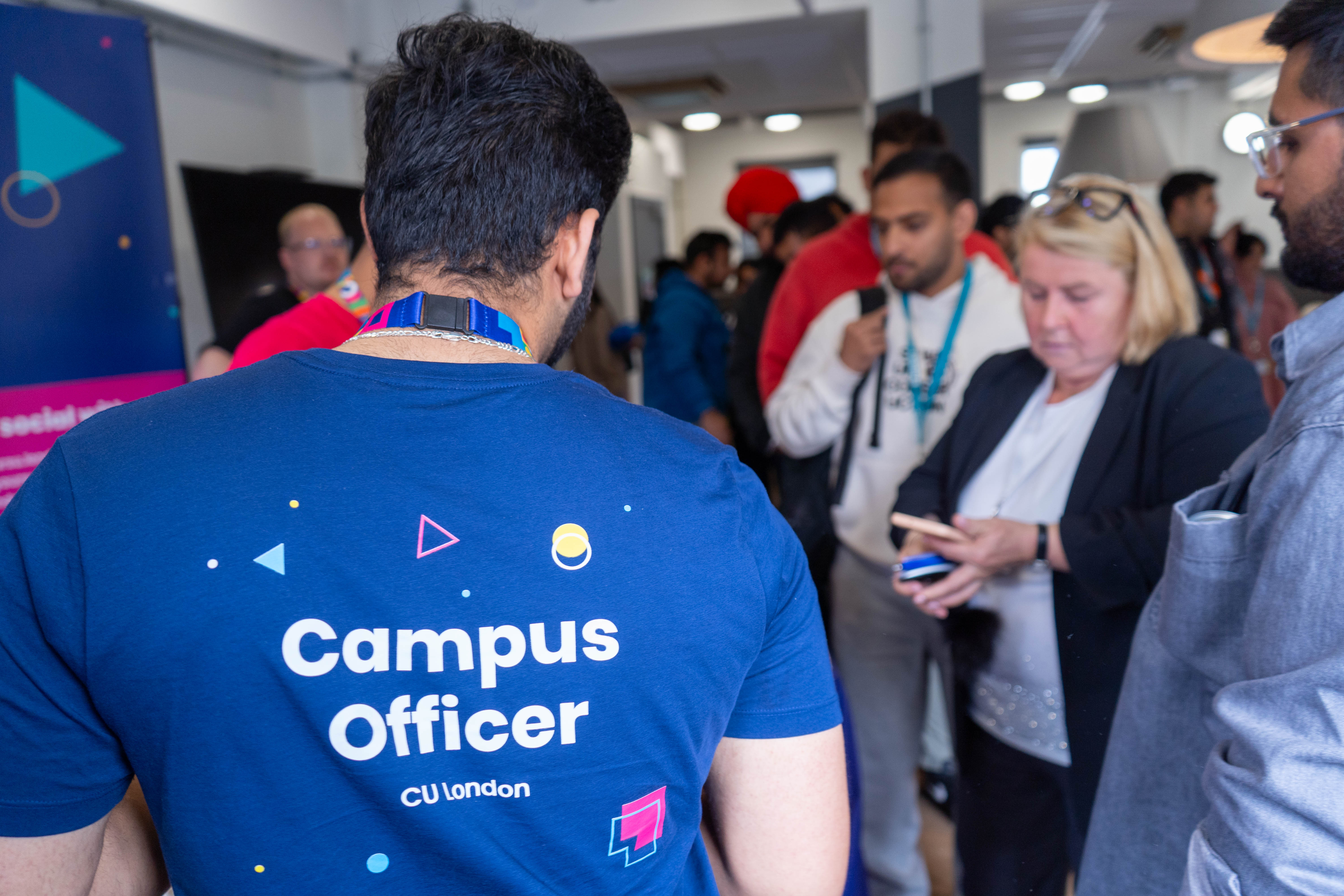 The back of a person wearing an SU-branded Campus Officer t-shirt.