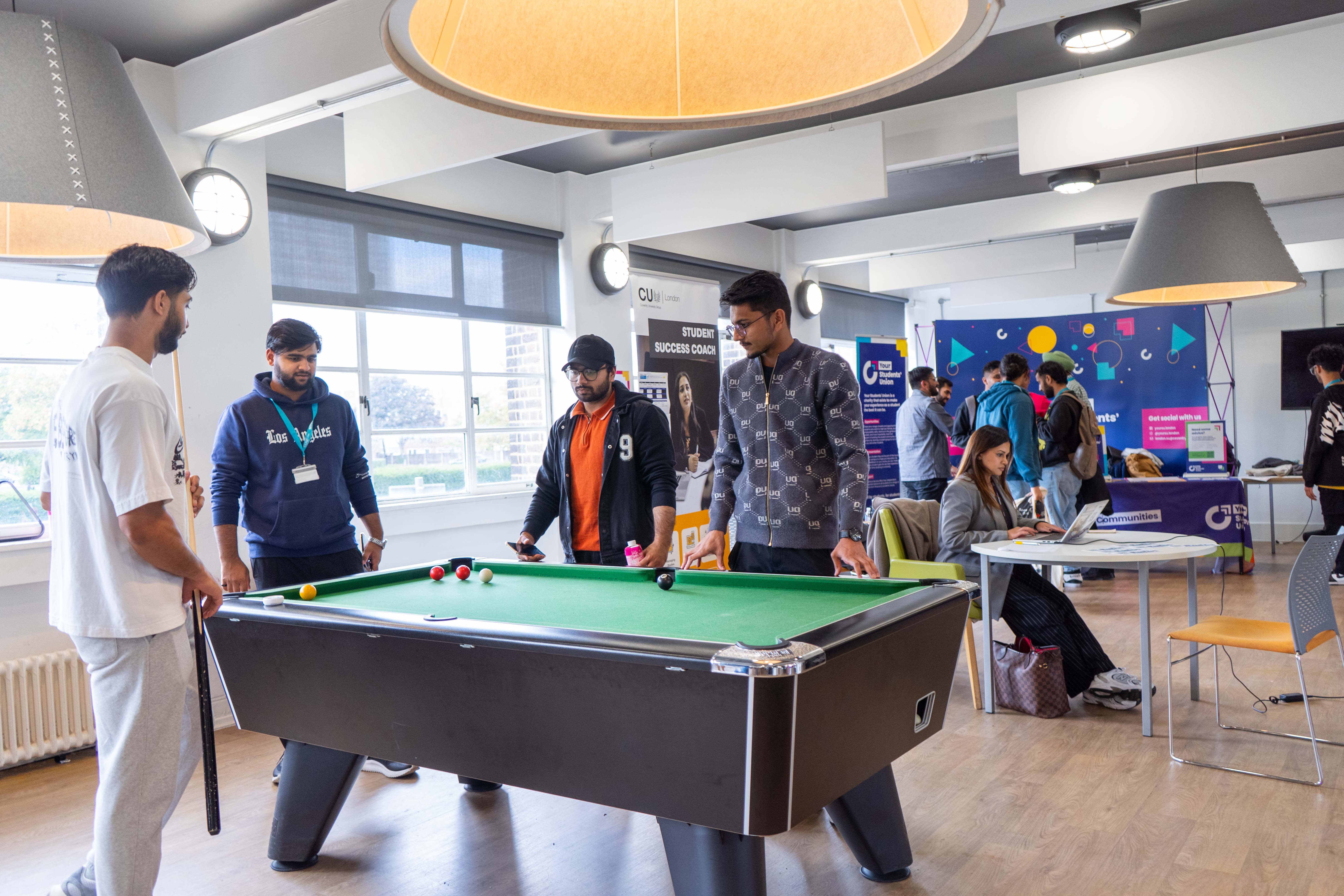 People standing over a pool table.