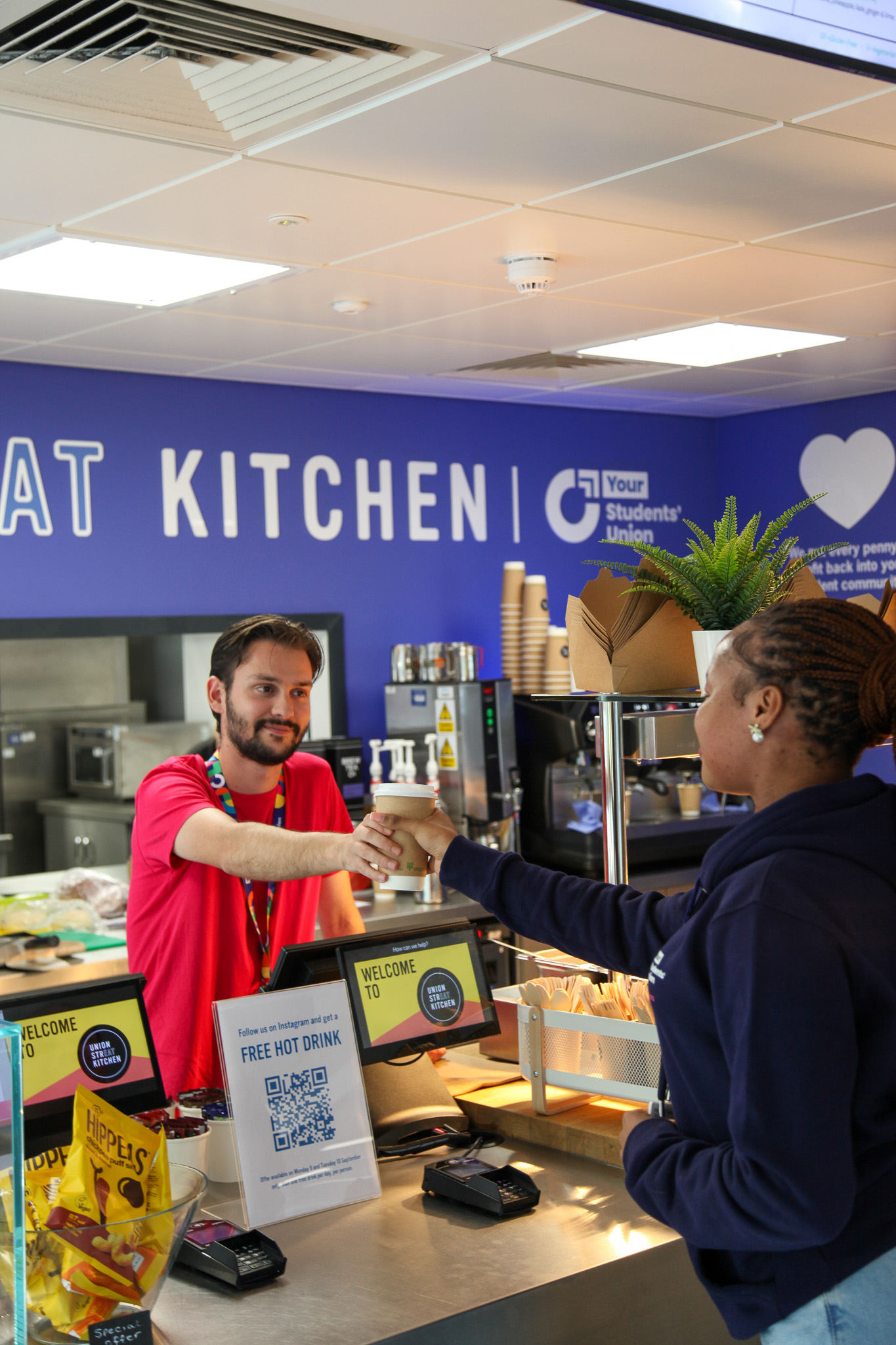 A barista handing over a coffee to a customer.