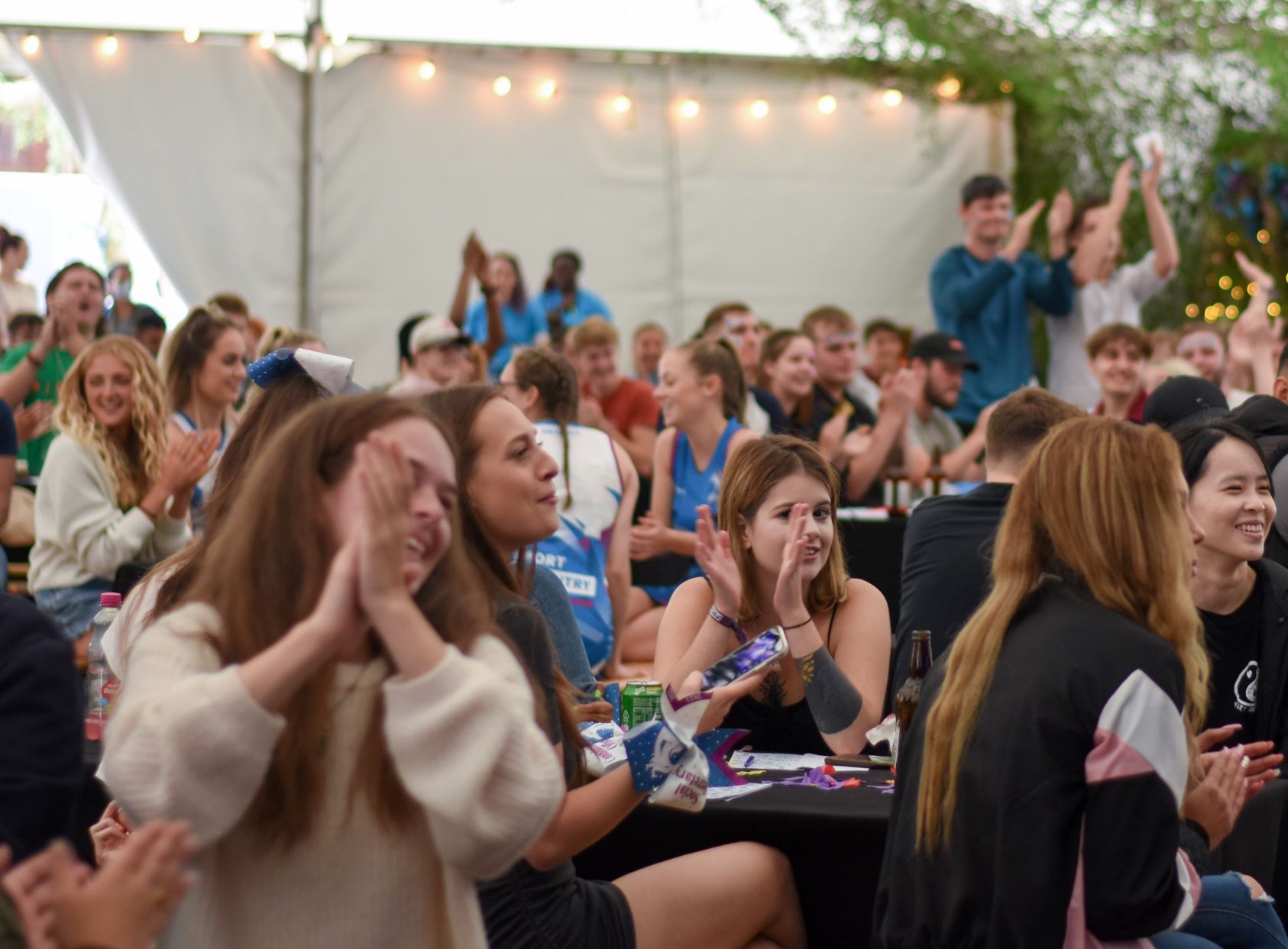 Female students sitting on the bench and applauding during the event.