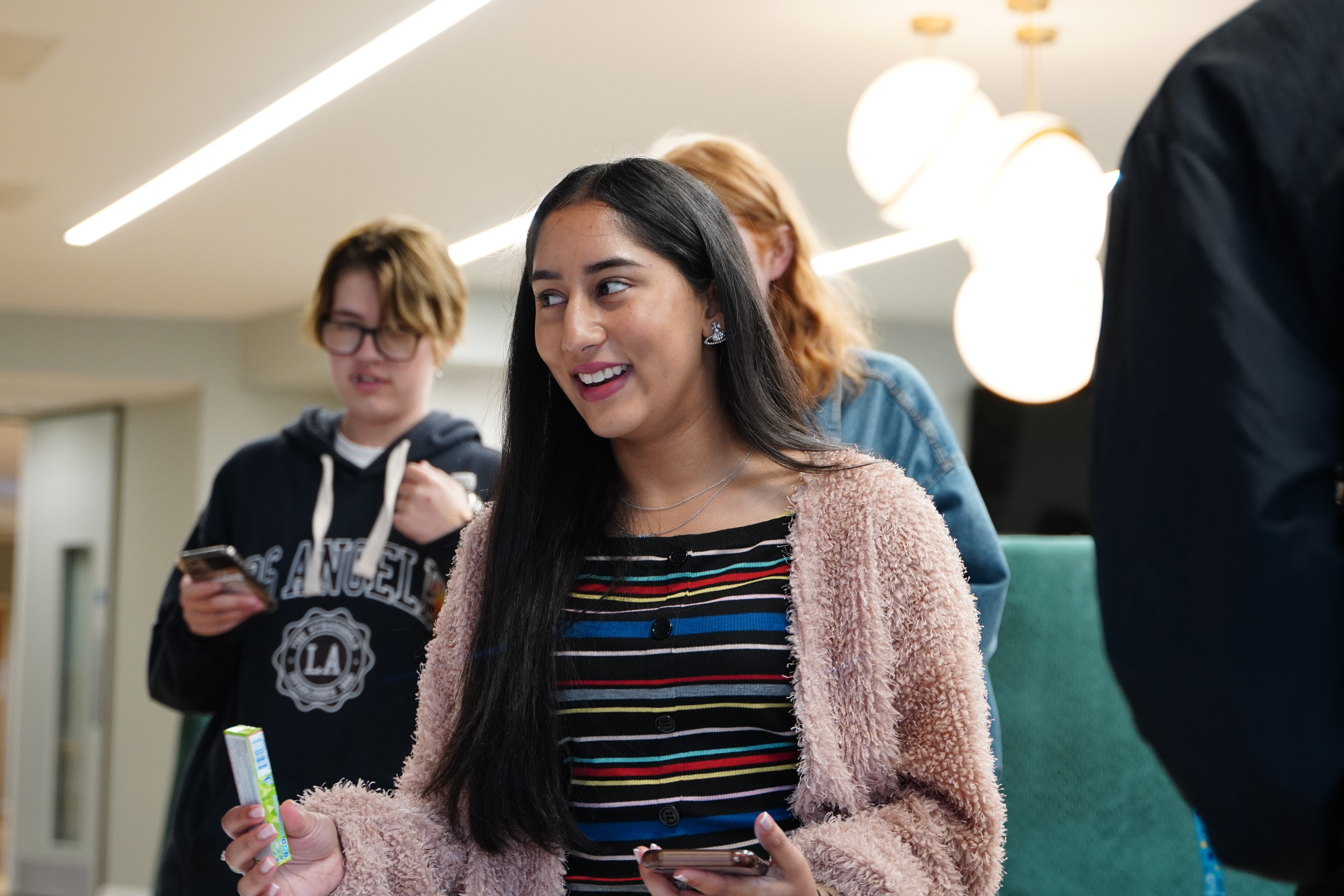 A student speaking to someone with an object in their right hand.