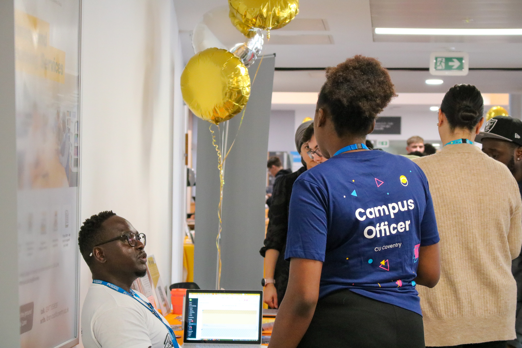 Two people - one wearing a hoodie with text reading: "Campus Officer CU Coventry" - engaging in a conversation.