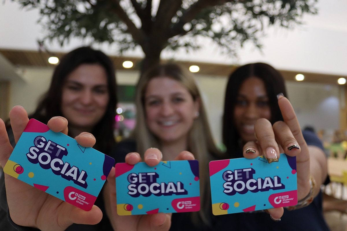 Bianca, Catherine, and Chisom holding Get Social Cards up to the camera lens