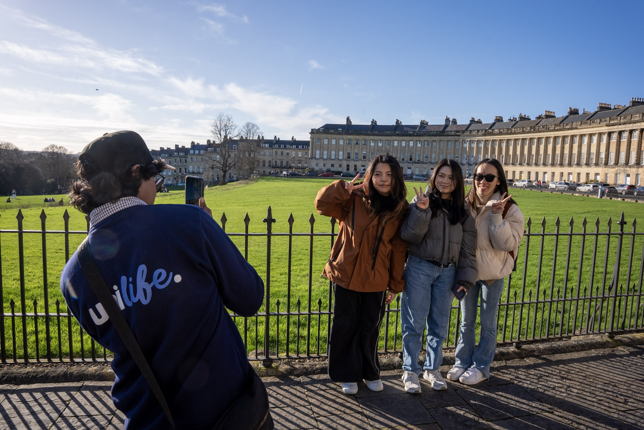 A person taking a picture of three other people on a mobile phone.