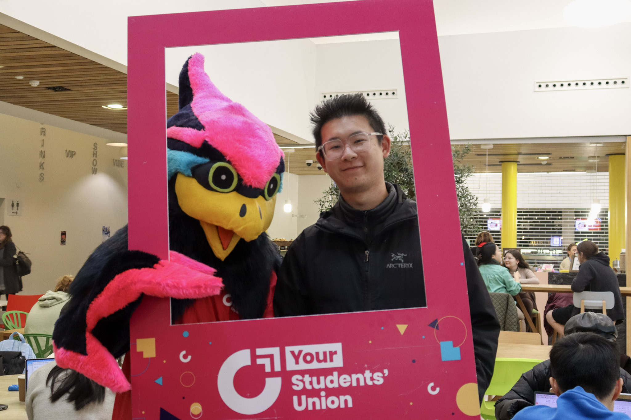 Coventry University Mascot Felix the Phoenix and a person holding a giant 'Your Students' Union' branded photograph template.